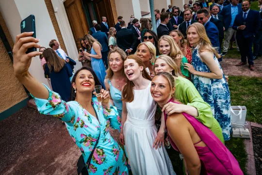 Grupp i festkläder tar en selfie utomhus
