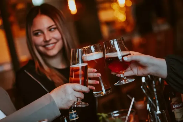 Leende kvinna skålar med ölglas på en bar