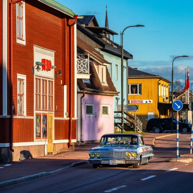 Veteranbil på gata med färgglada trähus i solsken