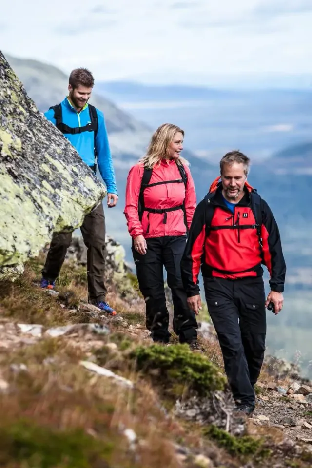 Tre vandrare går längs en bergssluttning