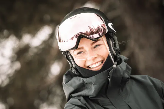 Leende person med skidhjälm och goggles