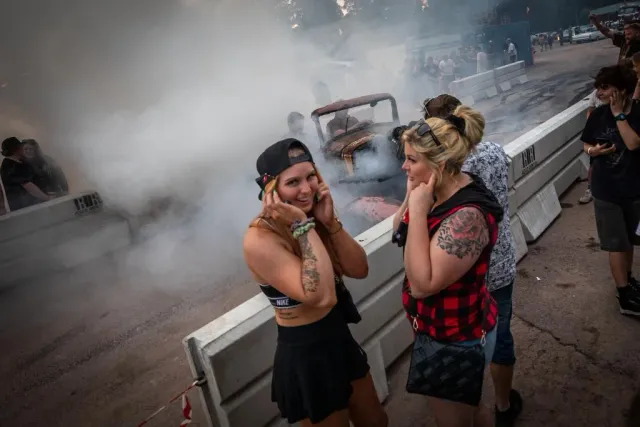 Två kvinnor tittar åt sidan vid rök på en festival