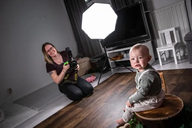 Fotograf med kamera på golvet och litet barn på en pall