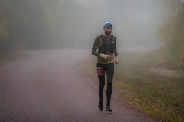 Löpare springer på en väg i dimma