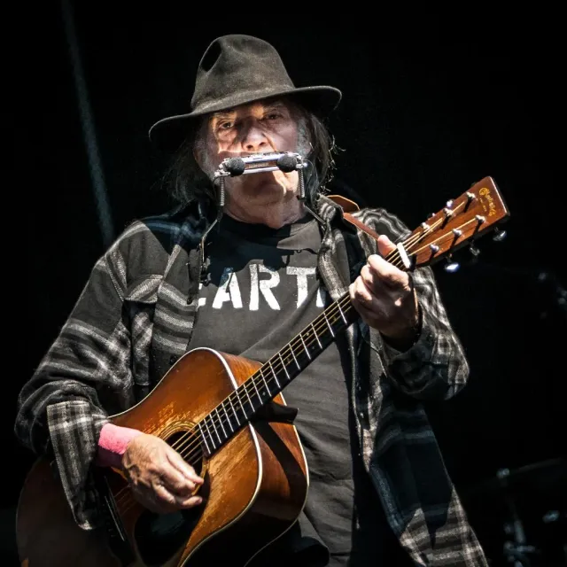 Man med hatt spelar gitarr och munspel