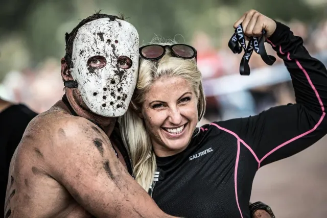 Maskerad man och leende kvinna kramas efter ett lopp