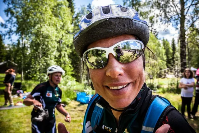 Leende person med cykelhjälm och solglasögon nära kameran
