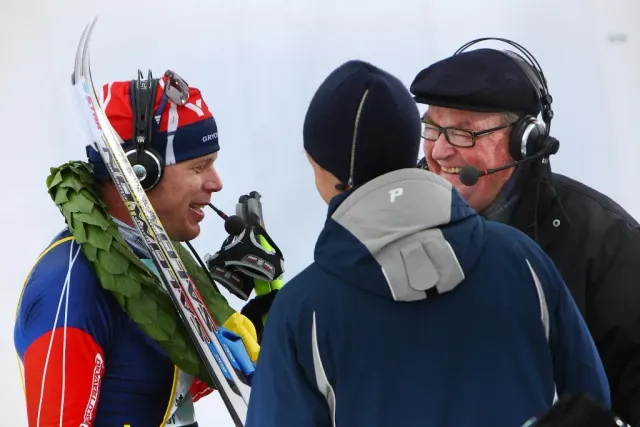 Skidåkare med lagerkrans samtalar med person med headset