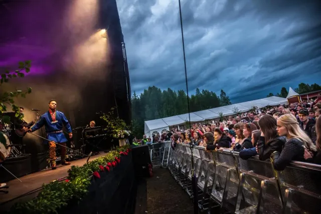 Konsert på utomhusscen med publik under mörka moln