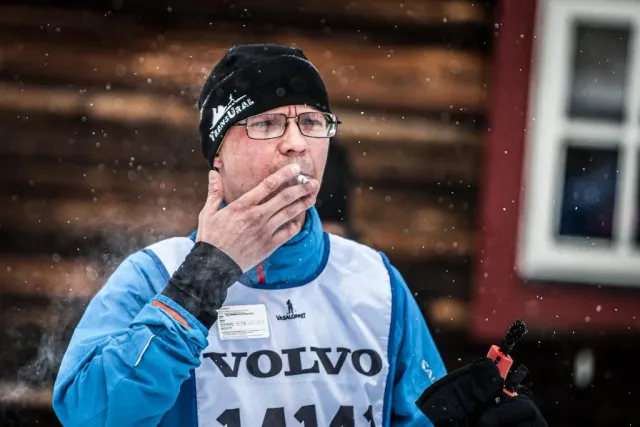 Man med mössa och startnummer håller handen vid munnen