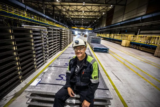 Man i hjälm sitter i en stor industrihall