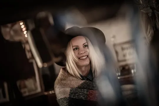 Leende kvinna med hatt och sjal i dunkel miljö
