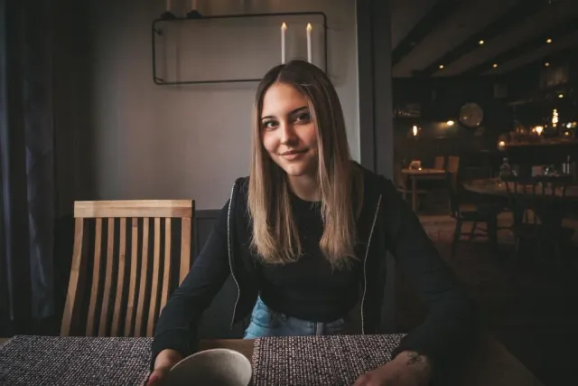 Ung kvinna sitter vid ett bord i en restaurang