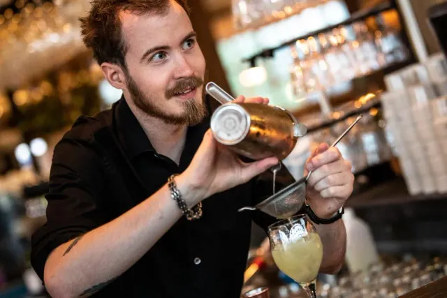 Bartender häller en drink ur en shaker