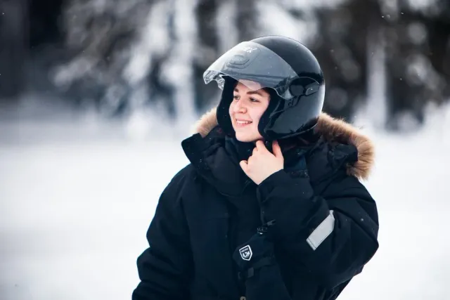 Person med hjälm och jacka med pälskrage i snöfall