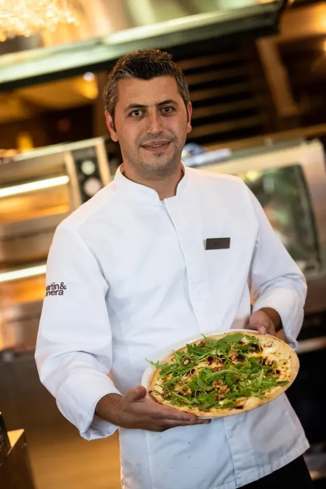 Kock i vit rock håller en tallrik med sallad
