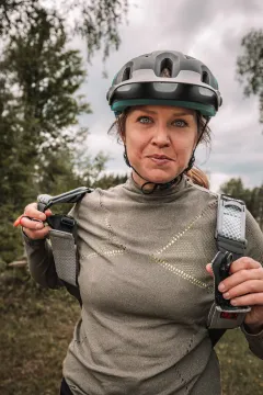 Kvinna med cykelhjälm håller i ryggsäckens remmar utomhus